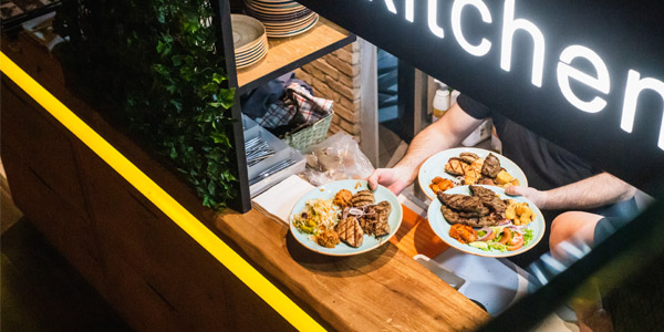 A restaurant employee serving up food at the pick up station