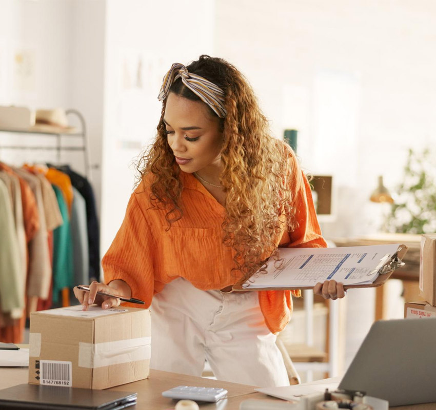 A woman with a piece of paper checking the order number on a package