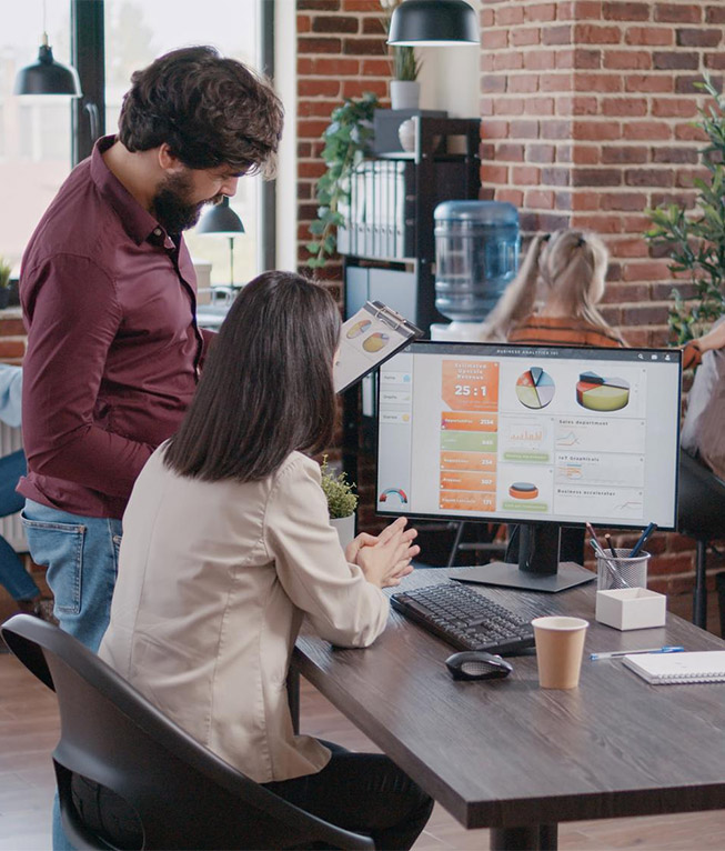 A woman showing a man some charts on her computer