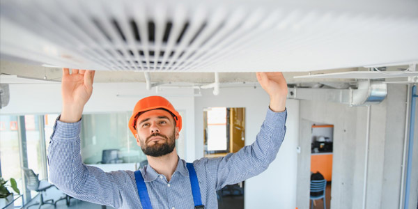 A man fixing a vent in an office building