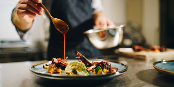A man pouring sauce over his dish