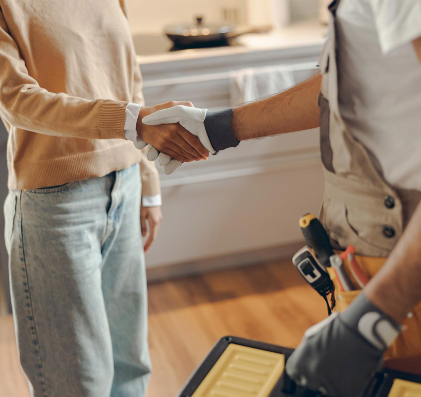 A handyman shaking hands with a women in her home