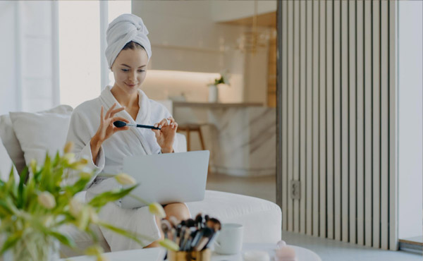 A woman in a robe and hair towel looking at her computer